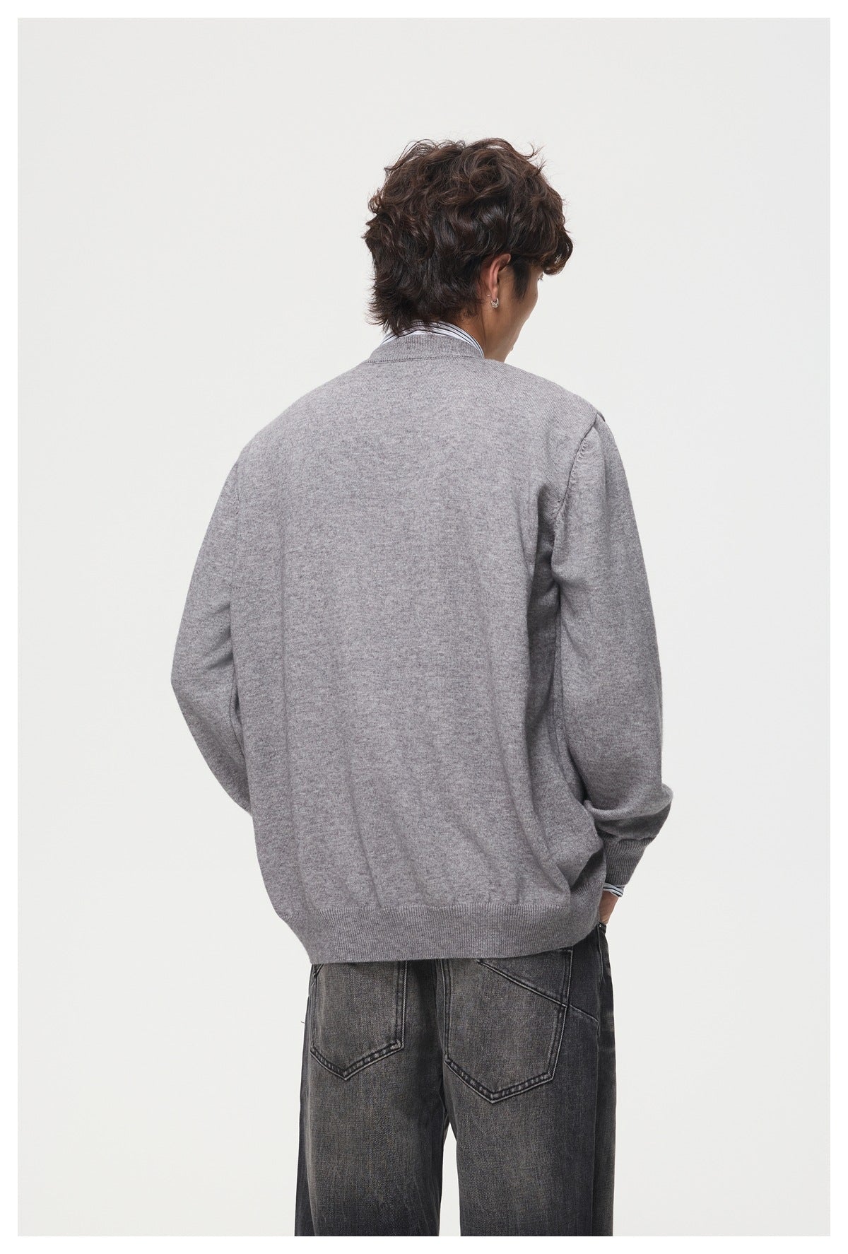 Back view of a model wearing a plain gray cardigan with ribbed cuffs and hem.