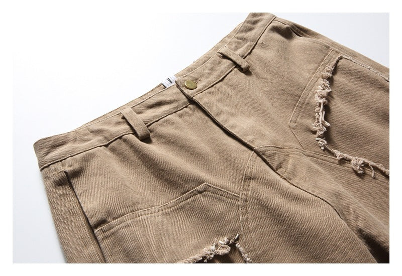 Close-up of tan shorts showing the waistband, button, pockets, and frayed seam detailing.
