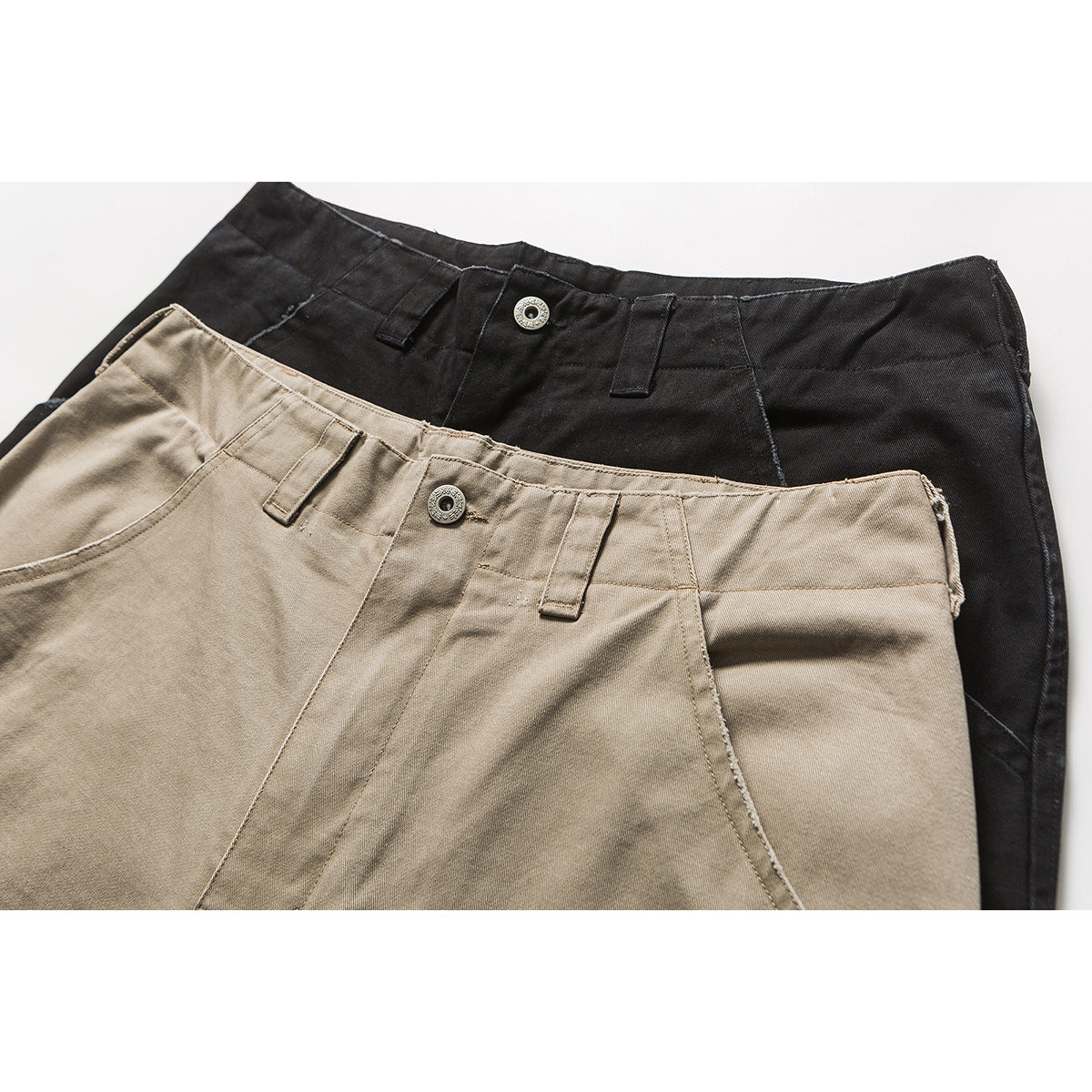 Close-up of beige and black cargo trousers showing the waistbands, belt loops, and metal buttons.