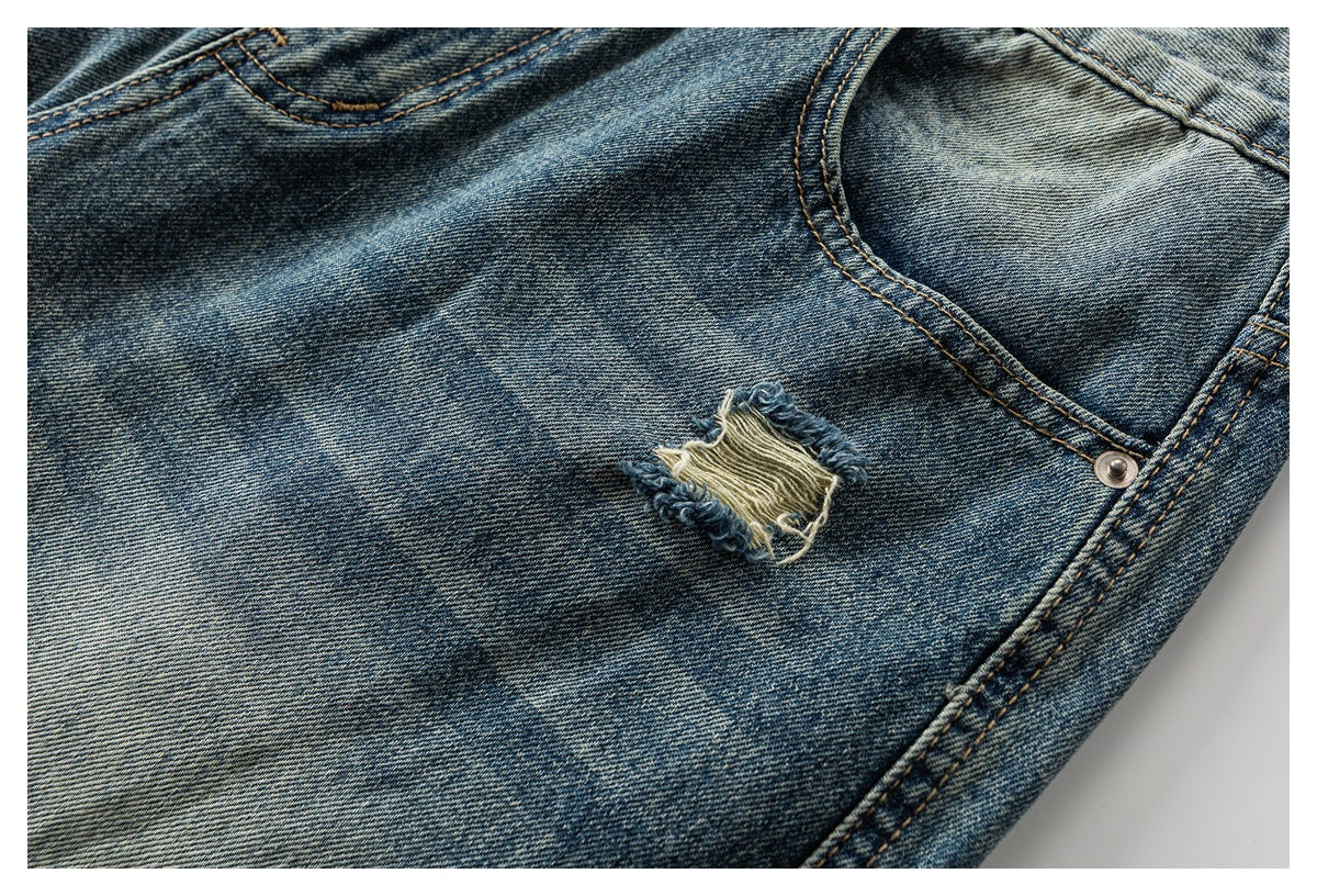 Close-up of faded blue jeans with a small frayed rip beside a curved pocket seam.