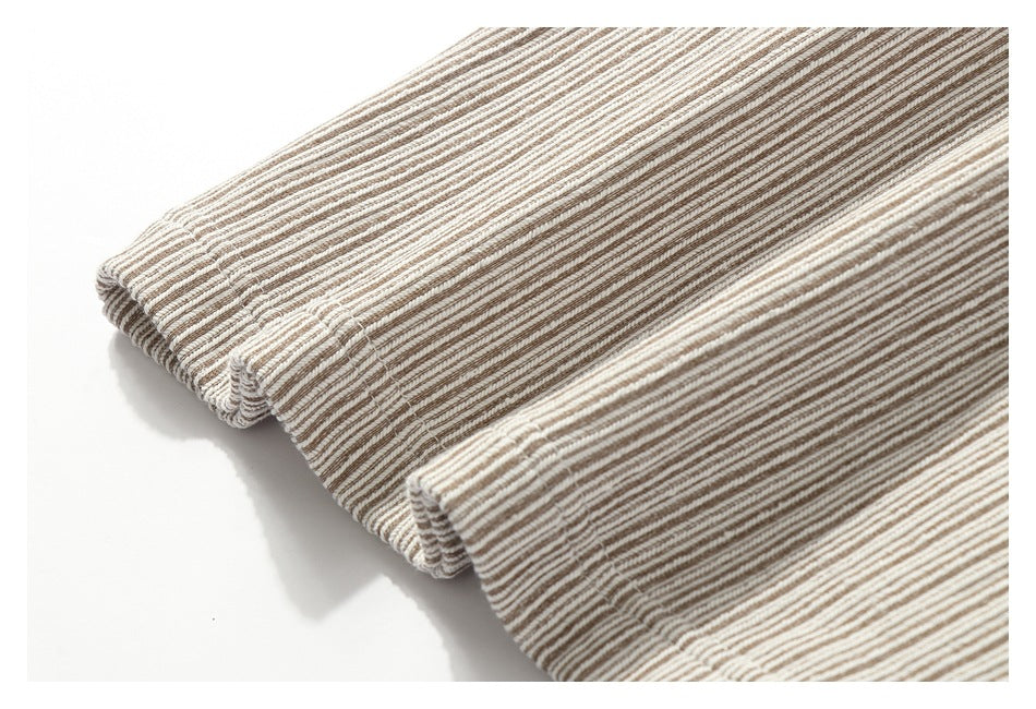 Close-up of several folded edges of cream and brown narrow-striped fabric.