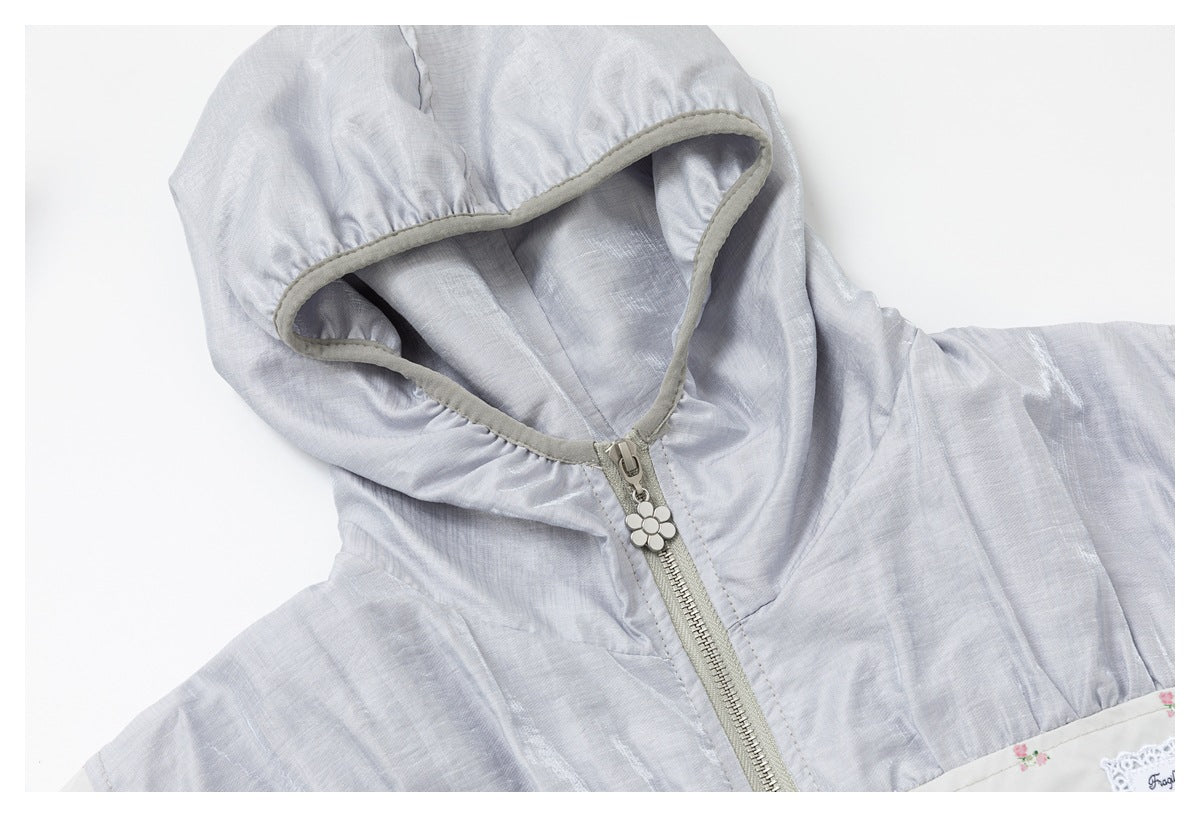 Close-up of the pale gray hood, gray-edged opening, zipper, and flower-shaped zipper pull.