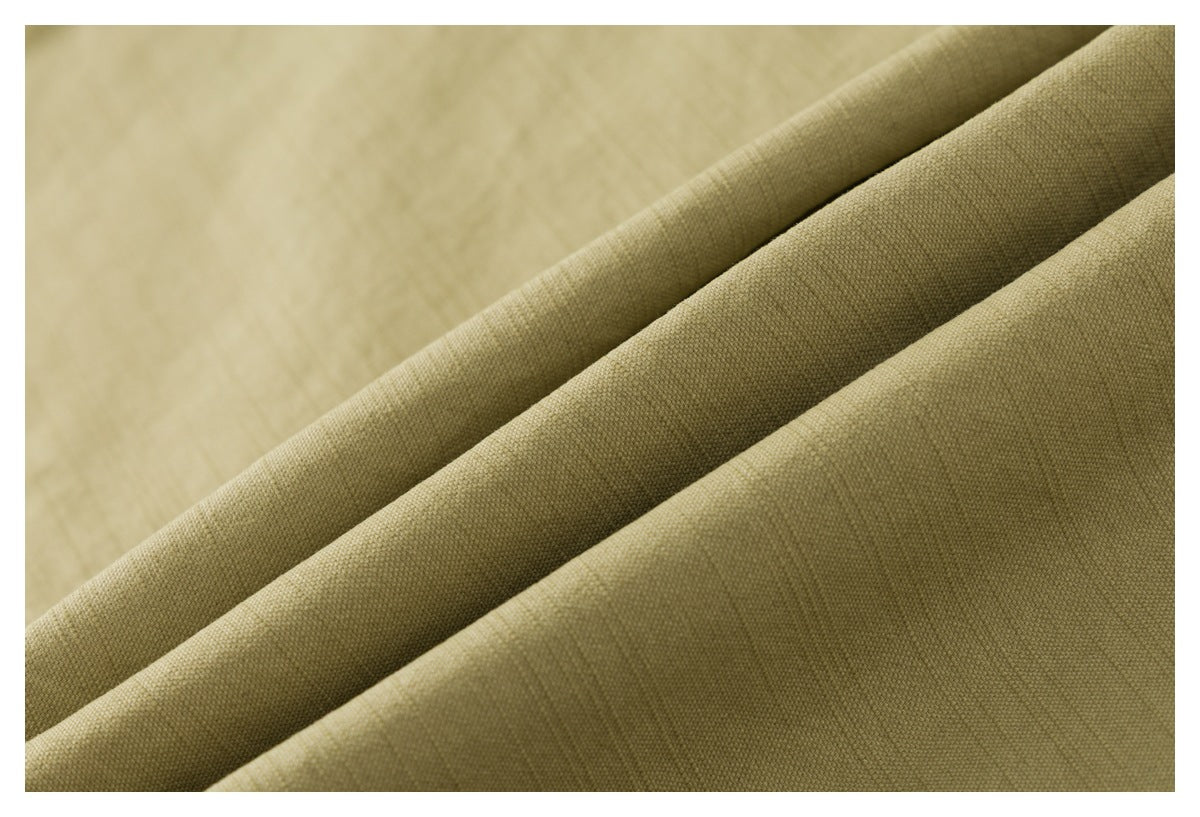 Close-up of khaki-beige woven fabric arranged in diagonal folds, showing its fine textured surface.
