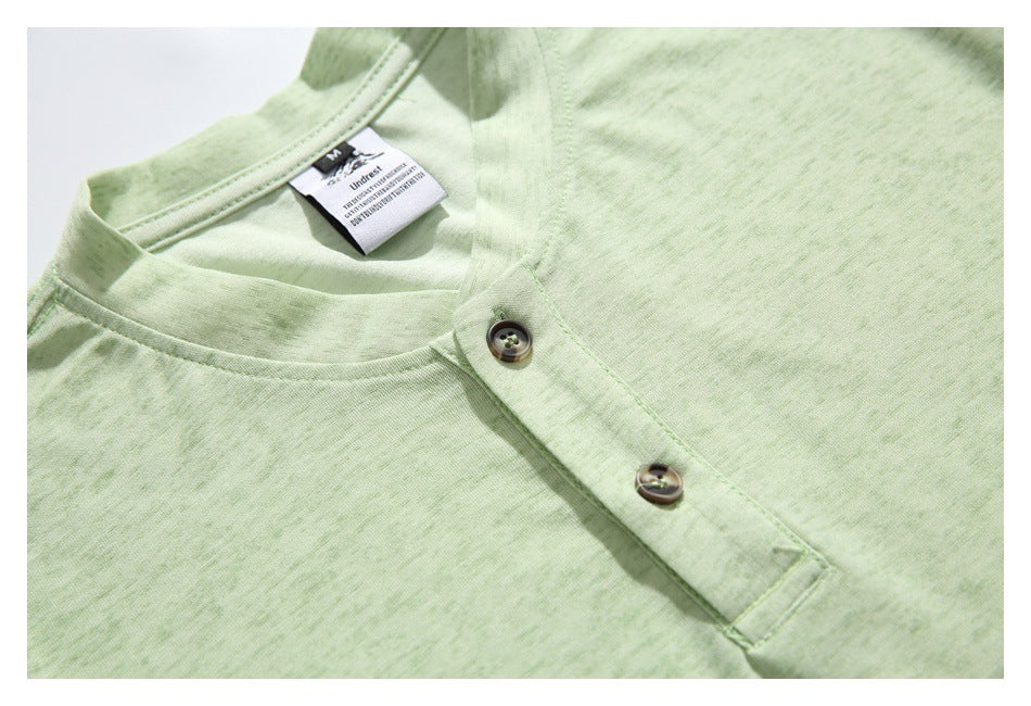 Close-up of the pale green shirt's band collar, two-button placket, and sewn neck label.