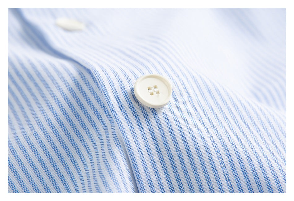 Close-up of a white button on blue-and-white striped shirt fabric.