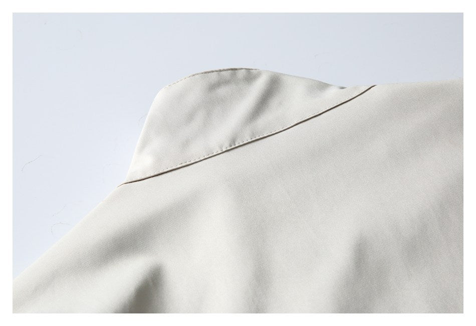 Close-up of an ivory garment's collar and curved stitched seam.