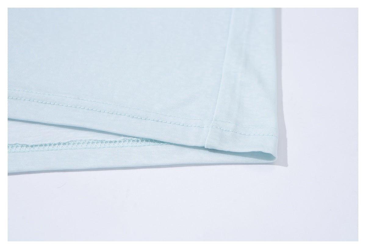 Close-up of the pale blue T-shirt's bottom hem, showing the stitching and overlocked inner seam.
