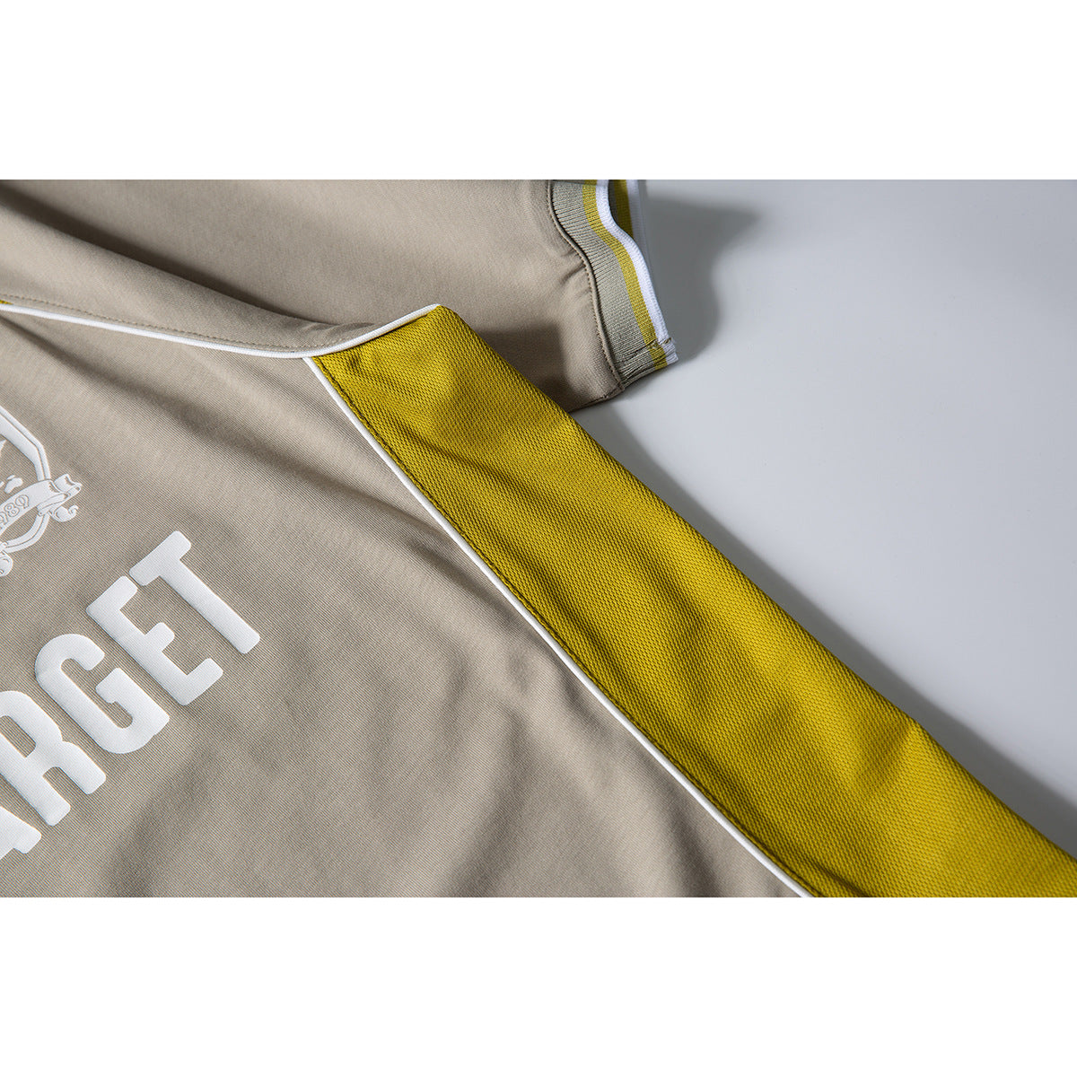Close-up of a taupe T-shirt with a yellow mesh side panel, white piping, and part of its white print.