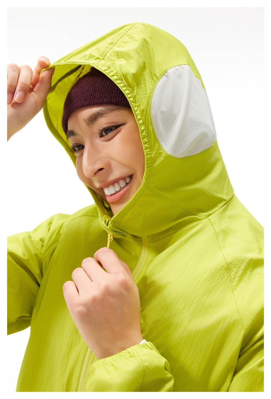 Close-up of a bright lime jacket's hood, showing a white mesh side panel and front zipper.