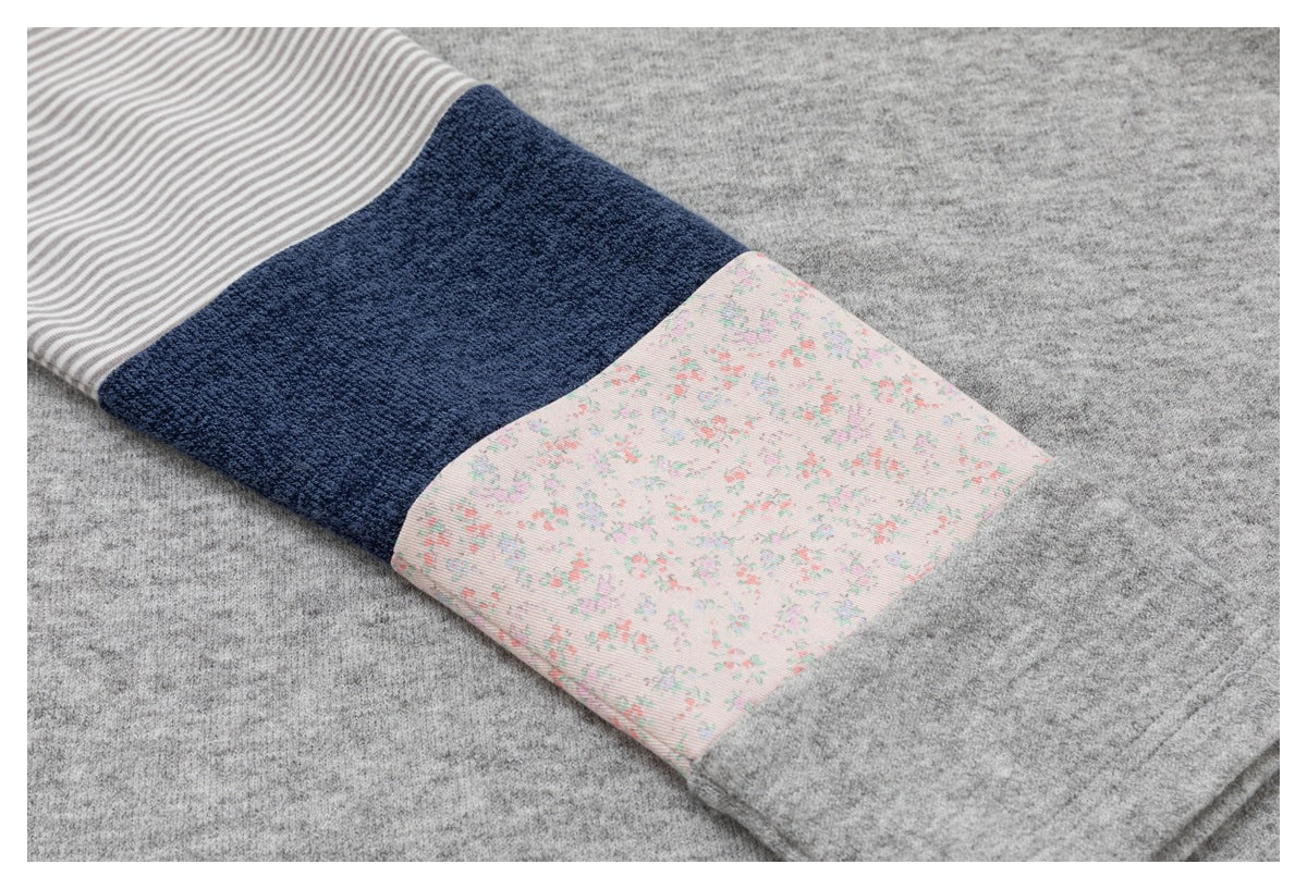 Close-up of a heather gray sleeve with striped, navy, and pale pink floral cuff panels.