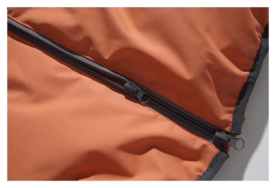 Close-up of a dark zipper running across the rust-orange jacket, with black edge trim.