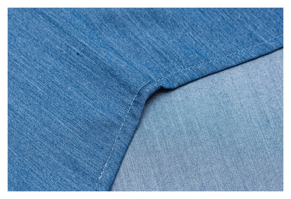 Close-up of blue denim fabric with a curved seam and light-colored stitching.