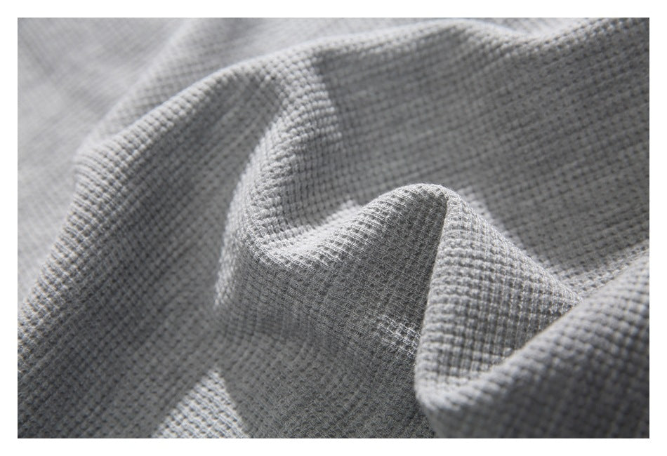 Extreme close-up of the light gray shirt's raised waffle-knit texture.