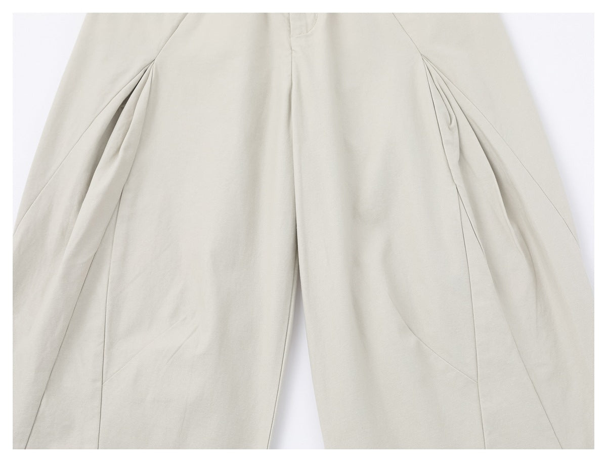 Close-up of the light ivory trouser legs showing curved seams and pleated side details.