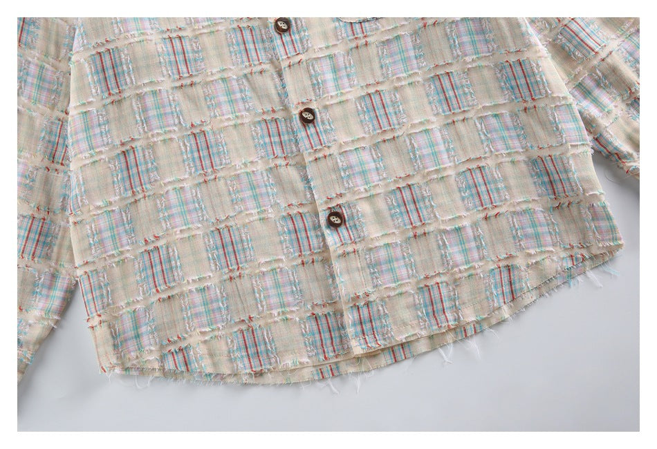 Close-up of the shirt's lower front, showing dark buttons, frayed plaid patchwork, and a curved hem.