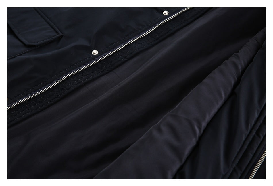 Close-up of a black garment showing a silver zipper, snap fasteners, and stitched panels.