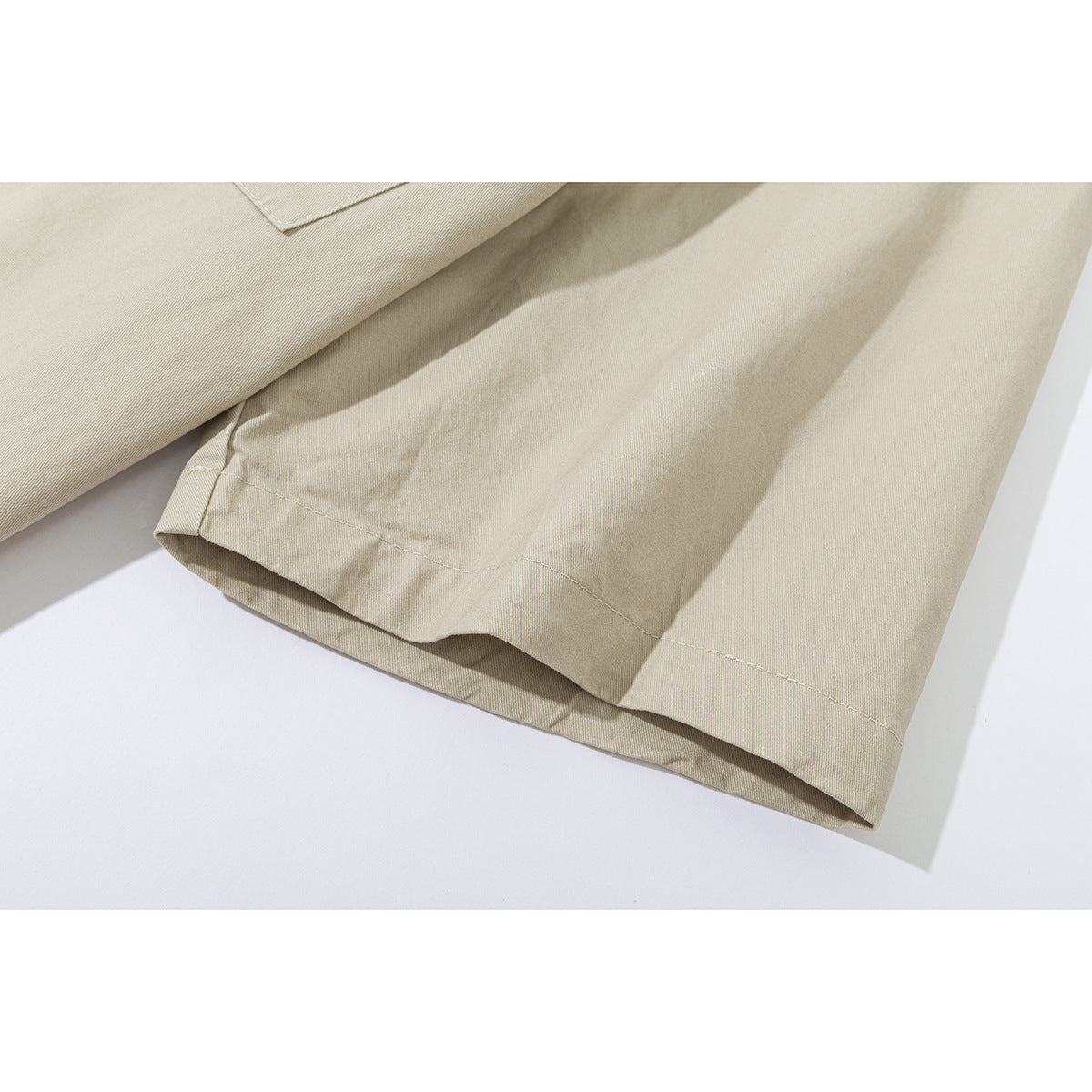 Close-up of the hem and sleeve edge of a light beige shirt.