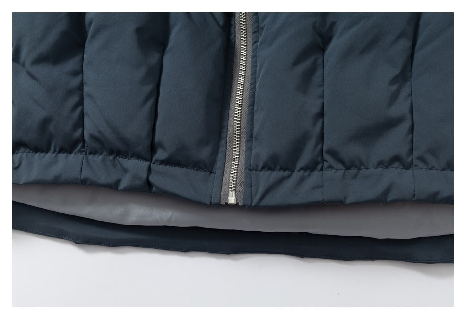 Close-up of a dark navy jacket's front zipper, quilted panels, and hem.