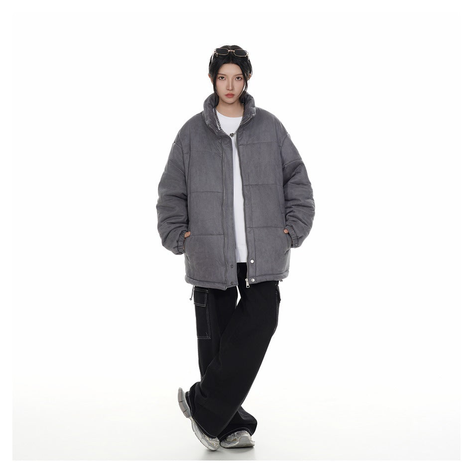 Model wearing a charcoal-gray quilted jacket with a stand collar, white top, black pants, and sneakers, front view.