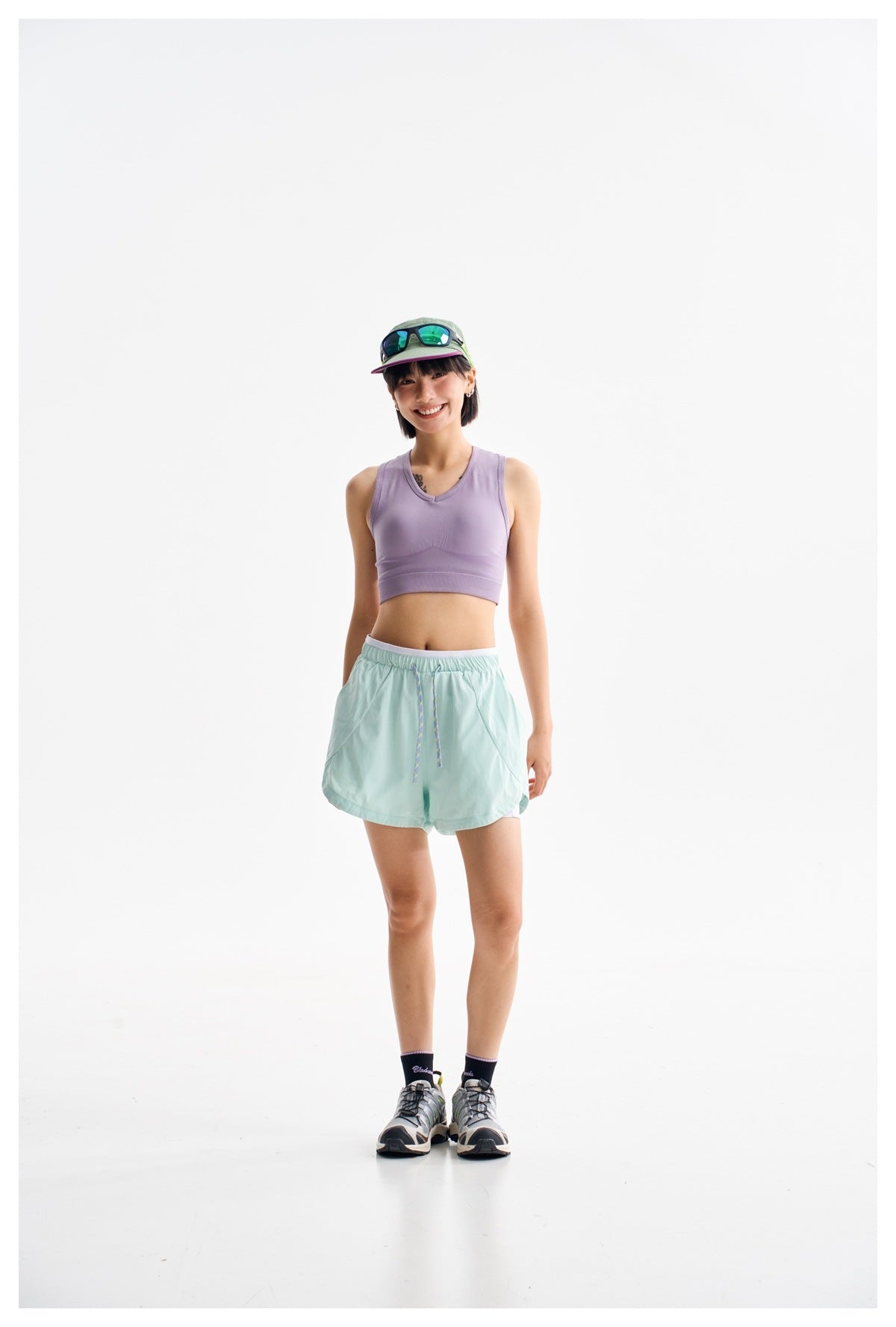 Full-length front view of a model in a lavender V-neck crop tank and mint drawstring shorts.