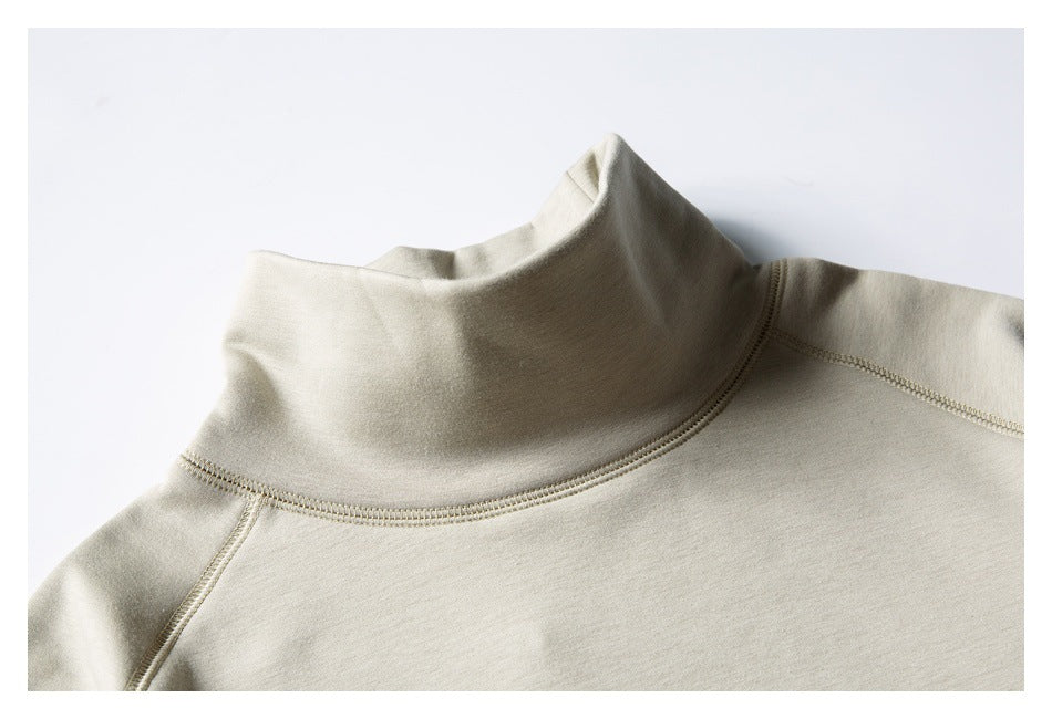 Close-up of a light beige sweatshirt's high collar and curved raglan shoulder seams.
