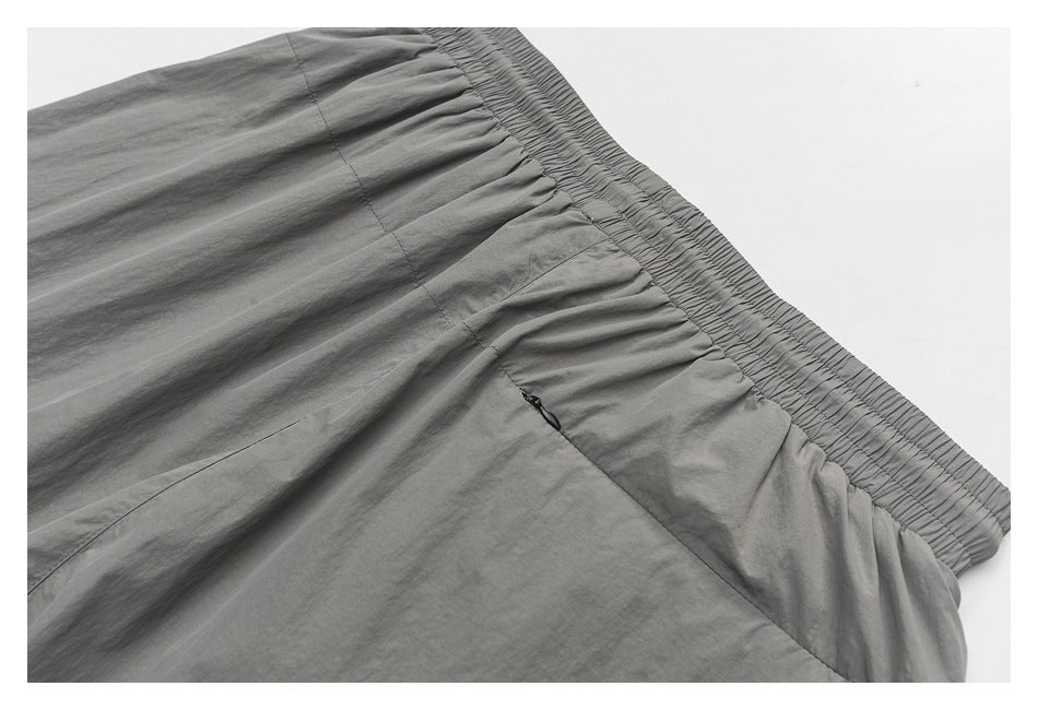 Close-up of gray shorts showing a wide elastic waistband and gathered fabric.