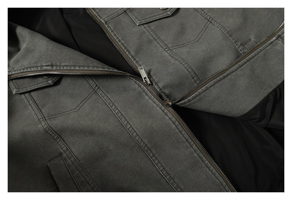 Close-up of the charcoal gray jacket front with chest flap pockets, stitching, and an open zipper over black lining.