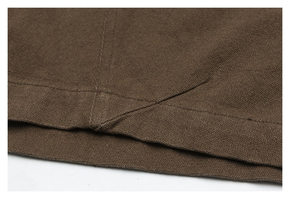 Close-up of a stitched seam and folded hem on the brown trousers.