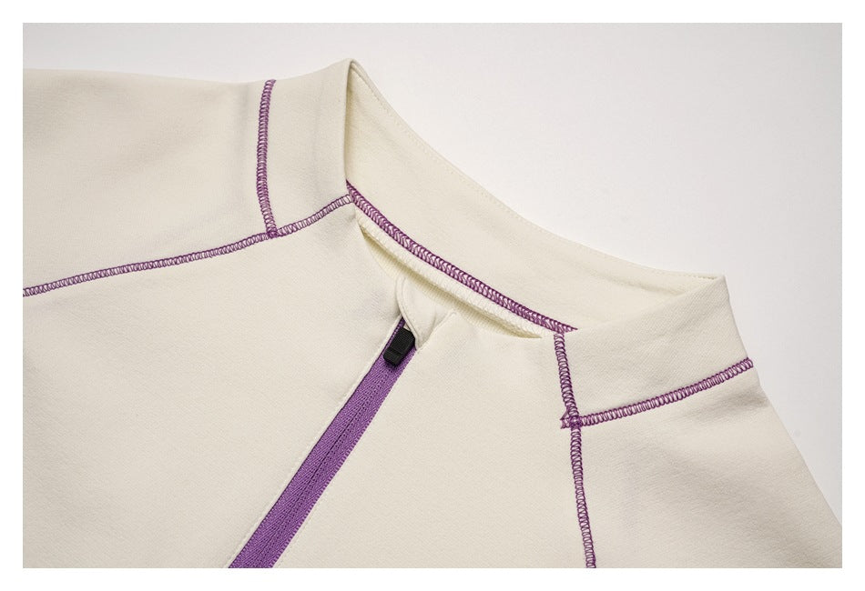 Close-up of the ivory top's collar, purple overlock stitching, and upper zipper.