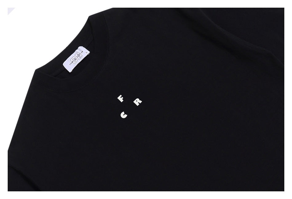 Close-up of a black T-shirt chest with small spaced white lettering and a visible neck label.