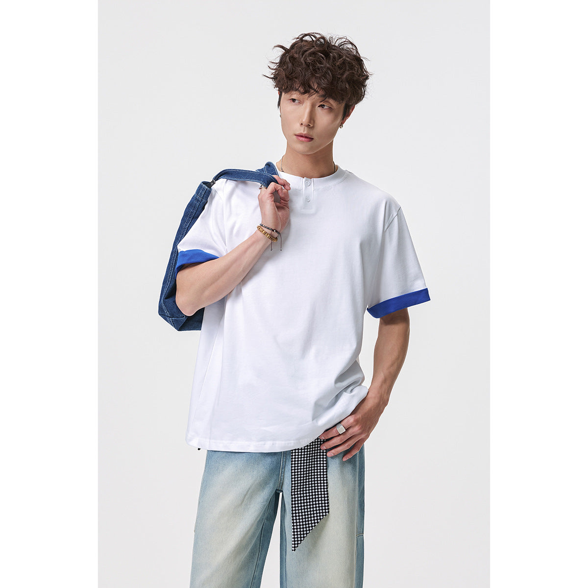 Model wearing a white short-sleeve Henley shirt with bright blue rolled cuffs.