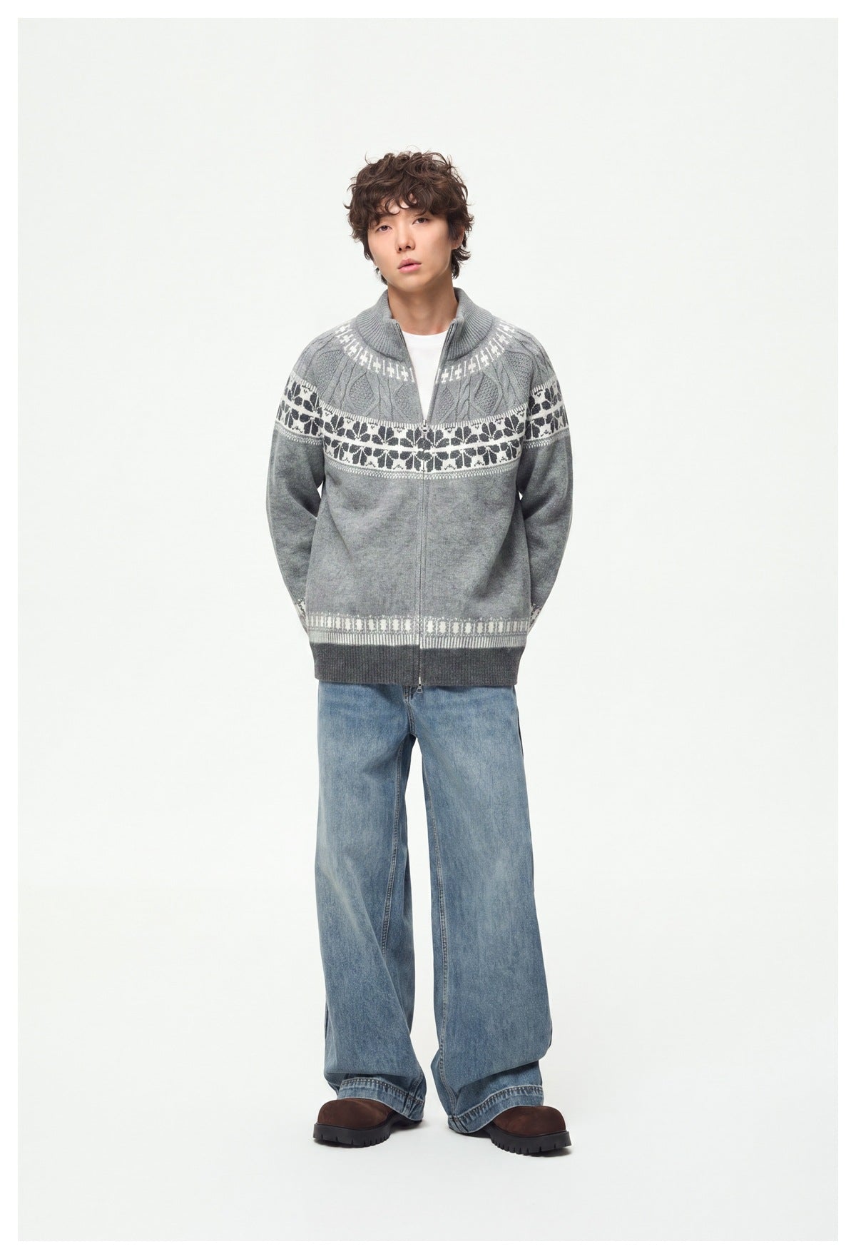 Model wearing a light gray full-zip knit cardigan with a high collar and white and dark patterned bands, with wide-leg jeans.