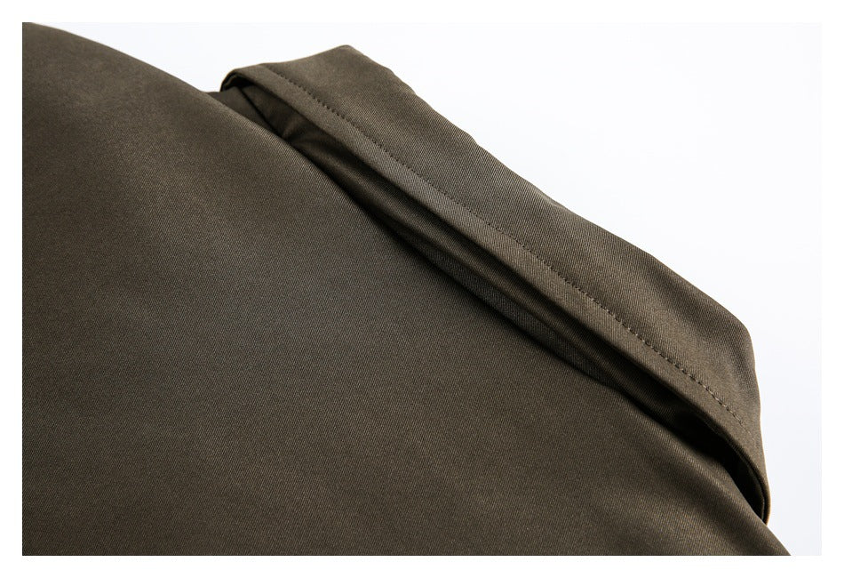 Close-up of an olive-brown garment's folded, stitched edge against a white background.