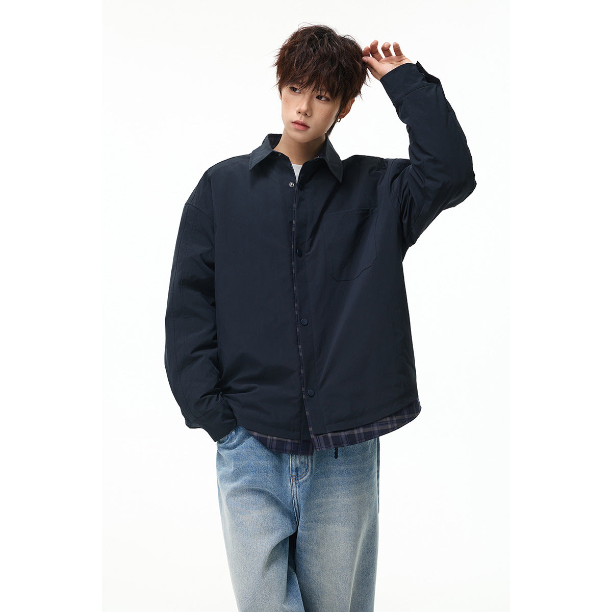 Model wearing an oversized dark navy button-front jacket with a chest pocket and plaid hem over light-wash jeans.