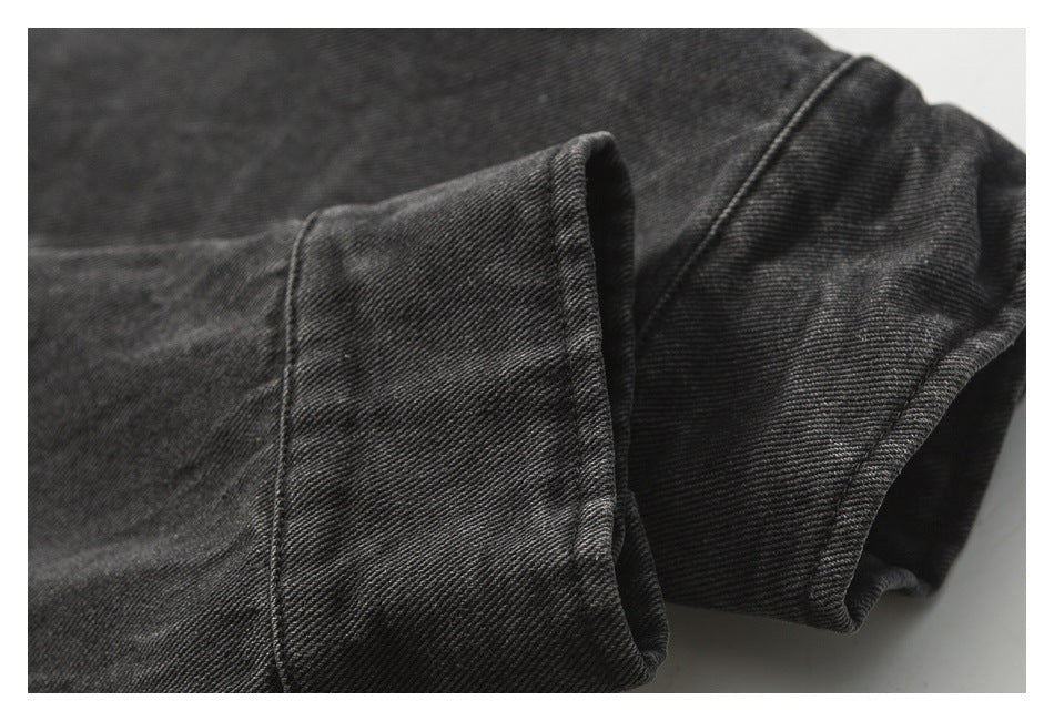 Close-up of a folded black denim sleeve cuff with visible twill texture and stitching.