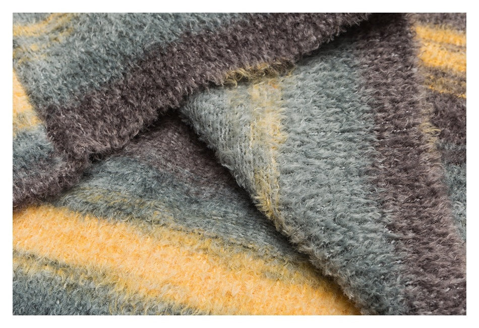 Close-up of folded fuzzy sweater fabric with gray, brown, and mustard stripes.