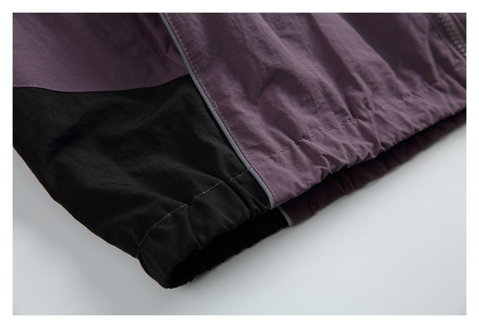 Close-up of the jacket's gathered plum hem, black color block, and dark piping.