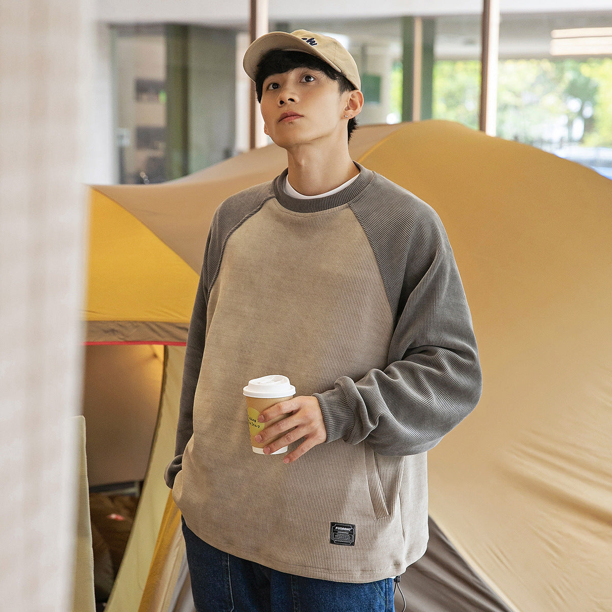 Model wearing a beige raglan sweatshirt with gray sleeves and a small hem label.