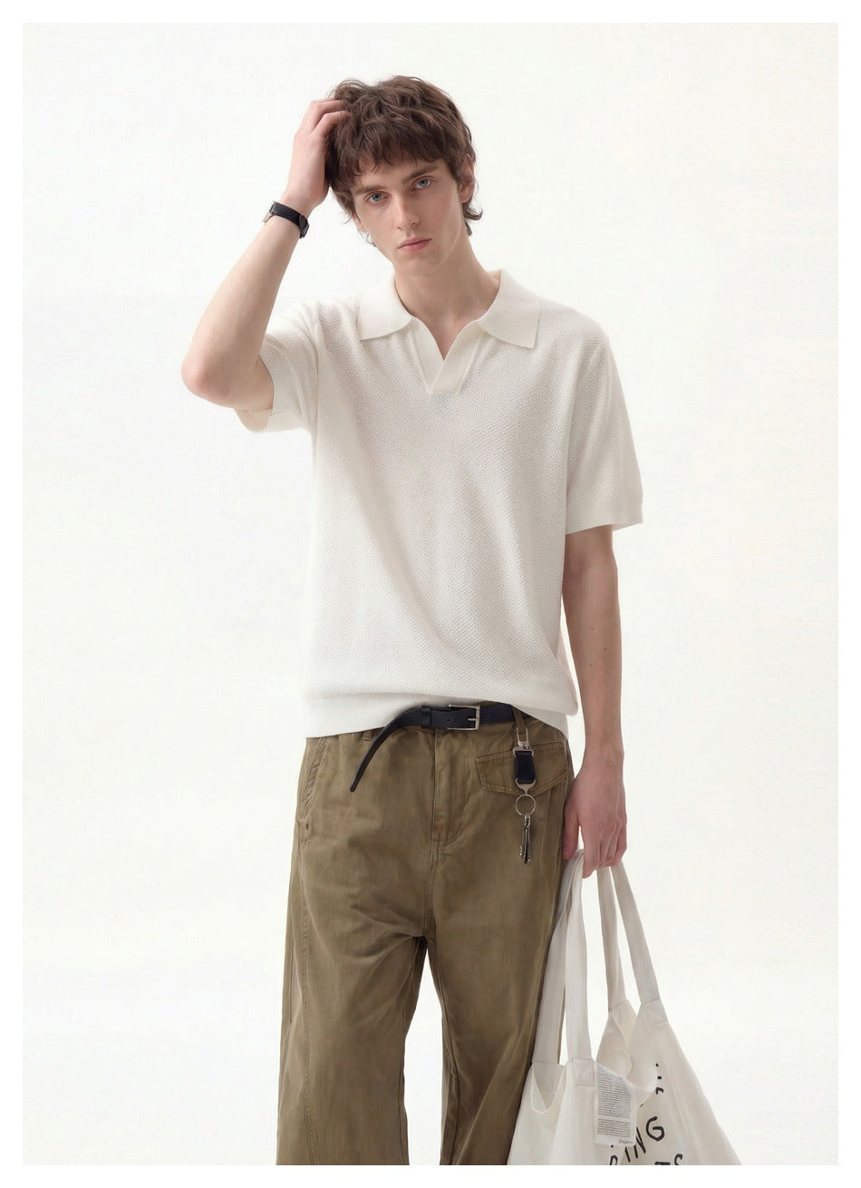Man modeling an ivory short-sleeve polo with olive trousers and a white tote bag.
