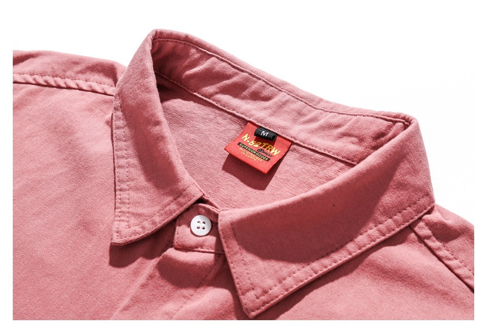 Close-up of the pink shirt's pointed collar, white button, and sewn-in neck label.