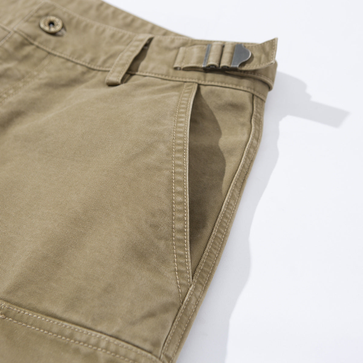Close-up of khaki wide-leg cargo pants showing the waistband adjuster, belt loop, and angled side pocket.