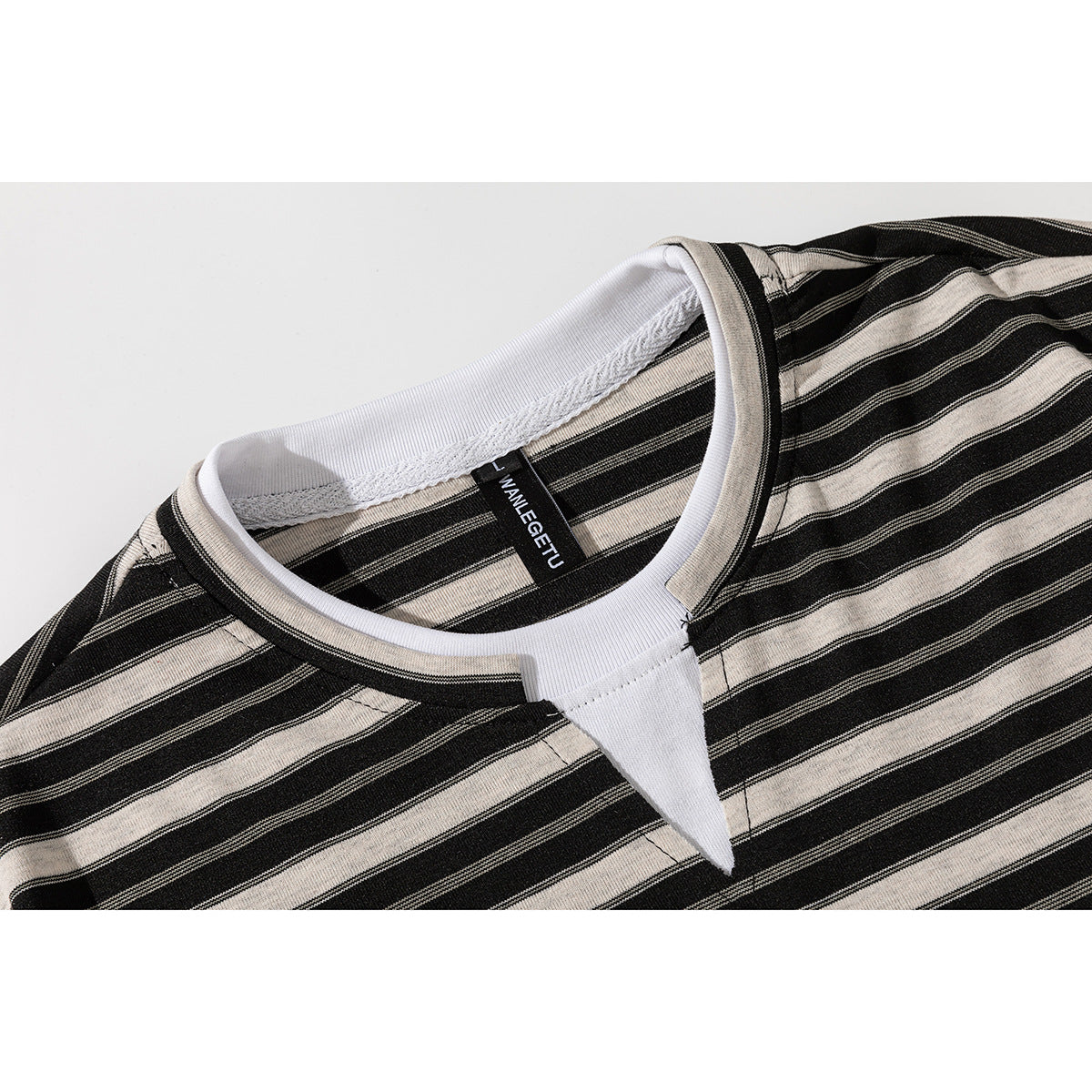 Close-up of a black and beige striped T-shirt neckline with white inner trim and a sewn neck label.