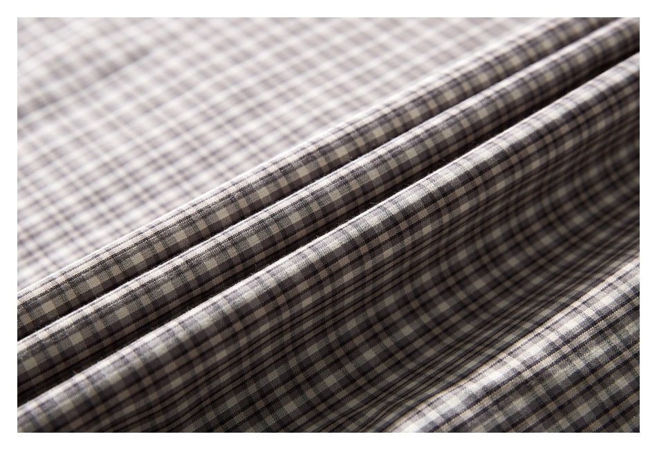 Close-up of gray and cream checked shirt fabric arranged in soft folds.