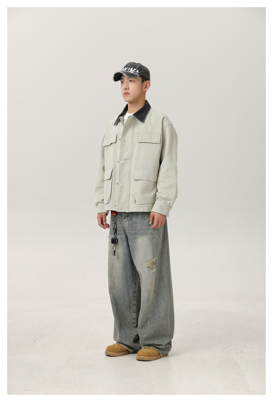 Side view of a model wearing a pale gray-green pocketed jacket with dark collar and faded jeans