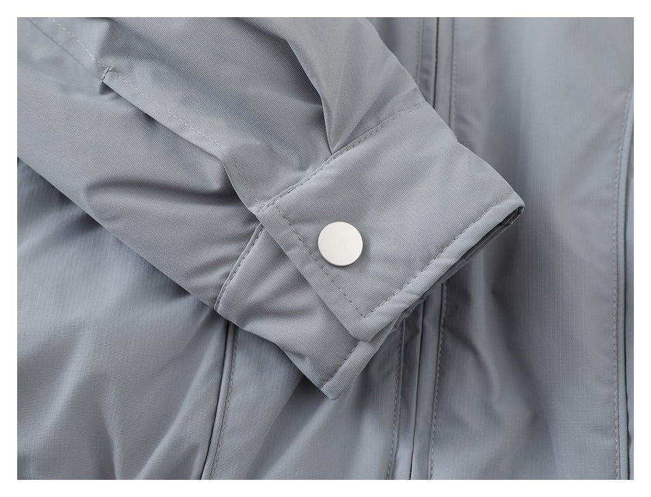 Close-up of a gray jacket sleeve cuff with a round white snap button and visible stitching.