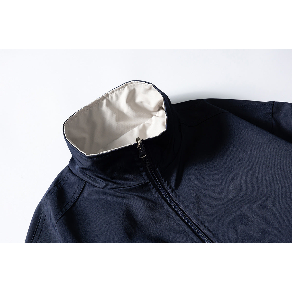 Close-up of a navy jacket’s stand collar with light lining and diagonal front zipper.