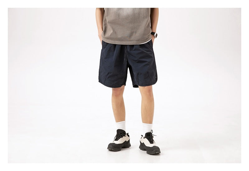 Front view of a person wearing dark navy knee-length shorts with a taupe top.