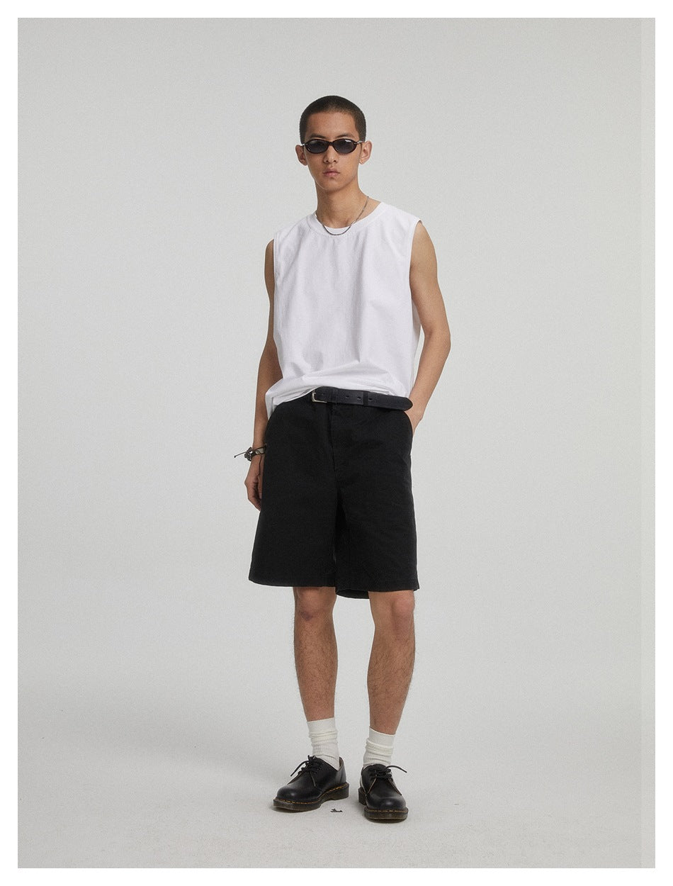 Model wearing black knee-length shorts with a white sleeveless shirt and black belt.