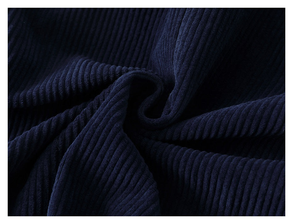 Close-up of dark navy ribbed corduroy fabric with deep folds.
