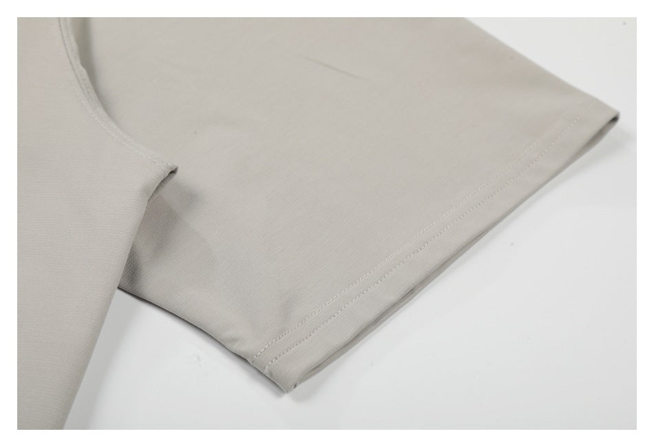 Close-up of the sleeve and double-stitched hem on a light gray T-shirt.